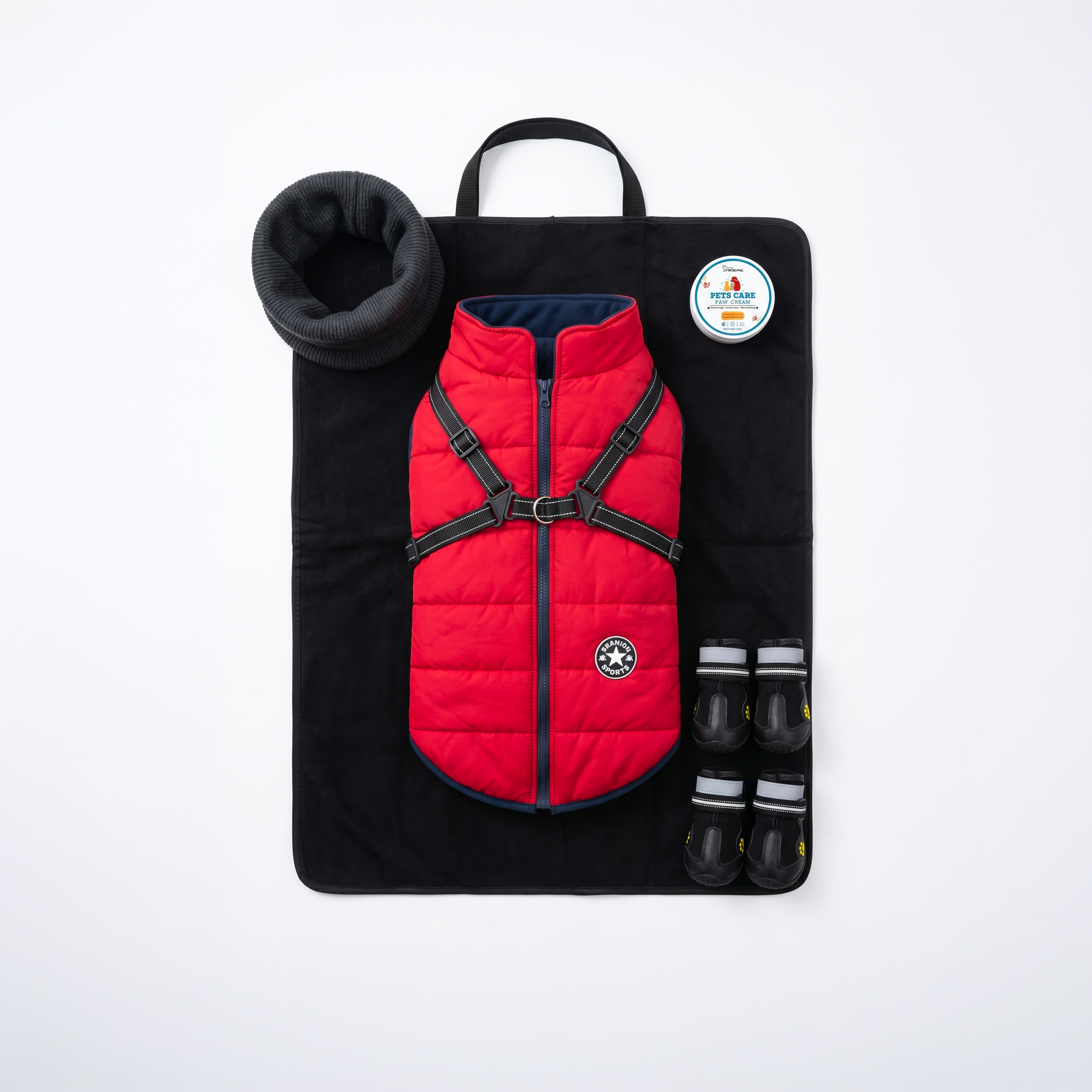 Contenu du pack grand froid complet pour chien avec manteau doudoune rouge imperméable et harnais intégré, cache-cou snood en tricot, baume de soin pour les coussinets, quatre bottines de protection neige et tapis isolant.